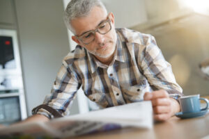 Middle-aged man in kitchen reading newspaper